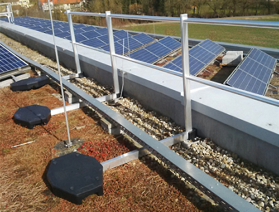 Flachdach mit montierten Solarpanelen und einem modularen Geländersystem als Absturzsicherung.
